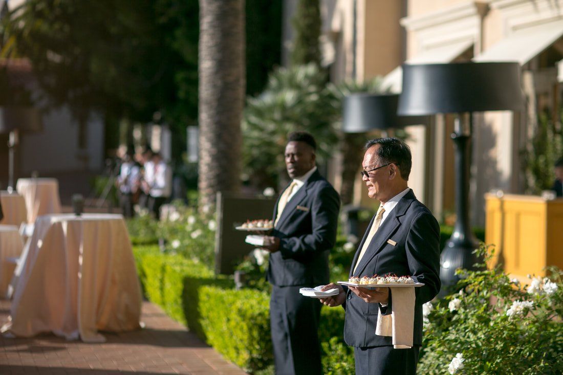 Two men in suits are standing next to each other holding trays of food.