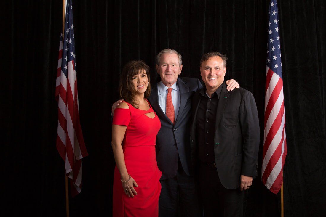 Three people are posing for a picture in front of american flags.