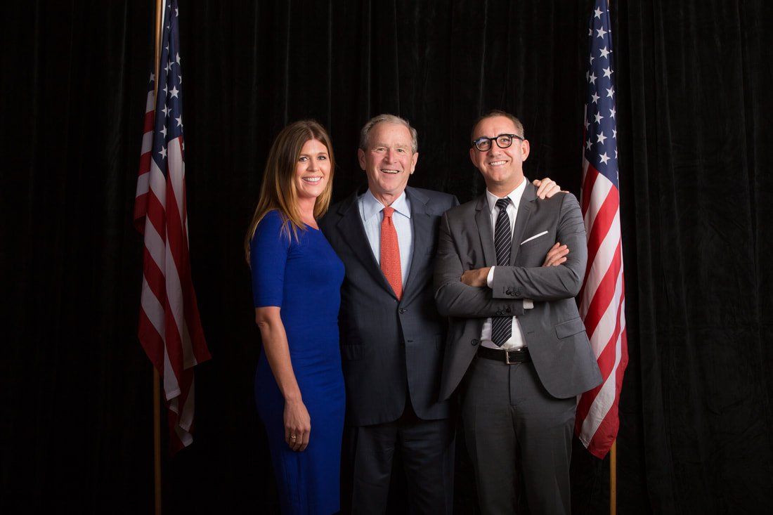 A man in a suit and tie is standing next to a woman in a blue dress and a man in a suit and tie.