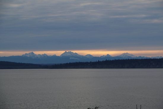 A lake with mountains in the background and a cloudy sky