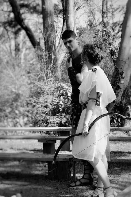 A man and a woman are standing next to each other holding bows and arrows.