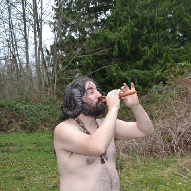A man with horns is playing a flute in a field, representing Pan.