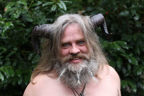 A man with long hair and a beard has horns on his head, representing Pan.