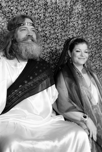 A man with a beard is sitting next to a woman in a white dress.
