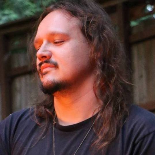 A man with long hair and a beard is wearing a black shirt, Dusty Dionne.