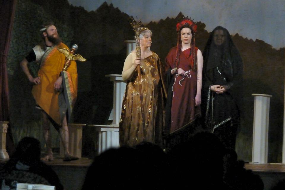 A group of people in costumes are standing on a stage at Spring Mysteries.