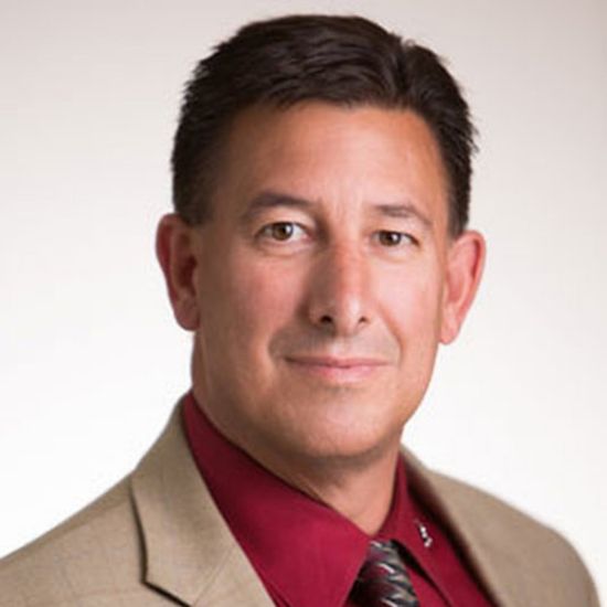 A man in a suit and tie is smiling for the camera