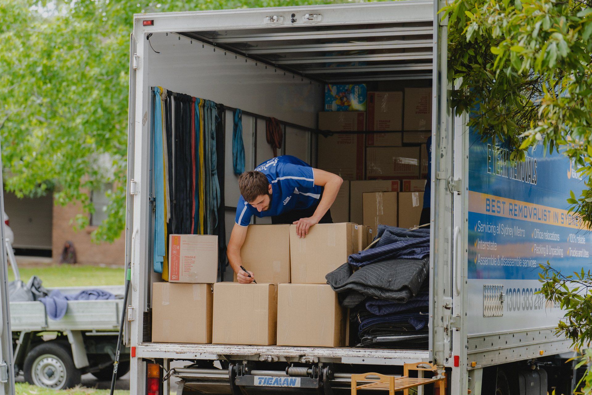 Person loading cardboard boxes into a moving truck with open back doors