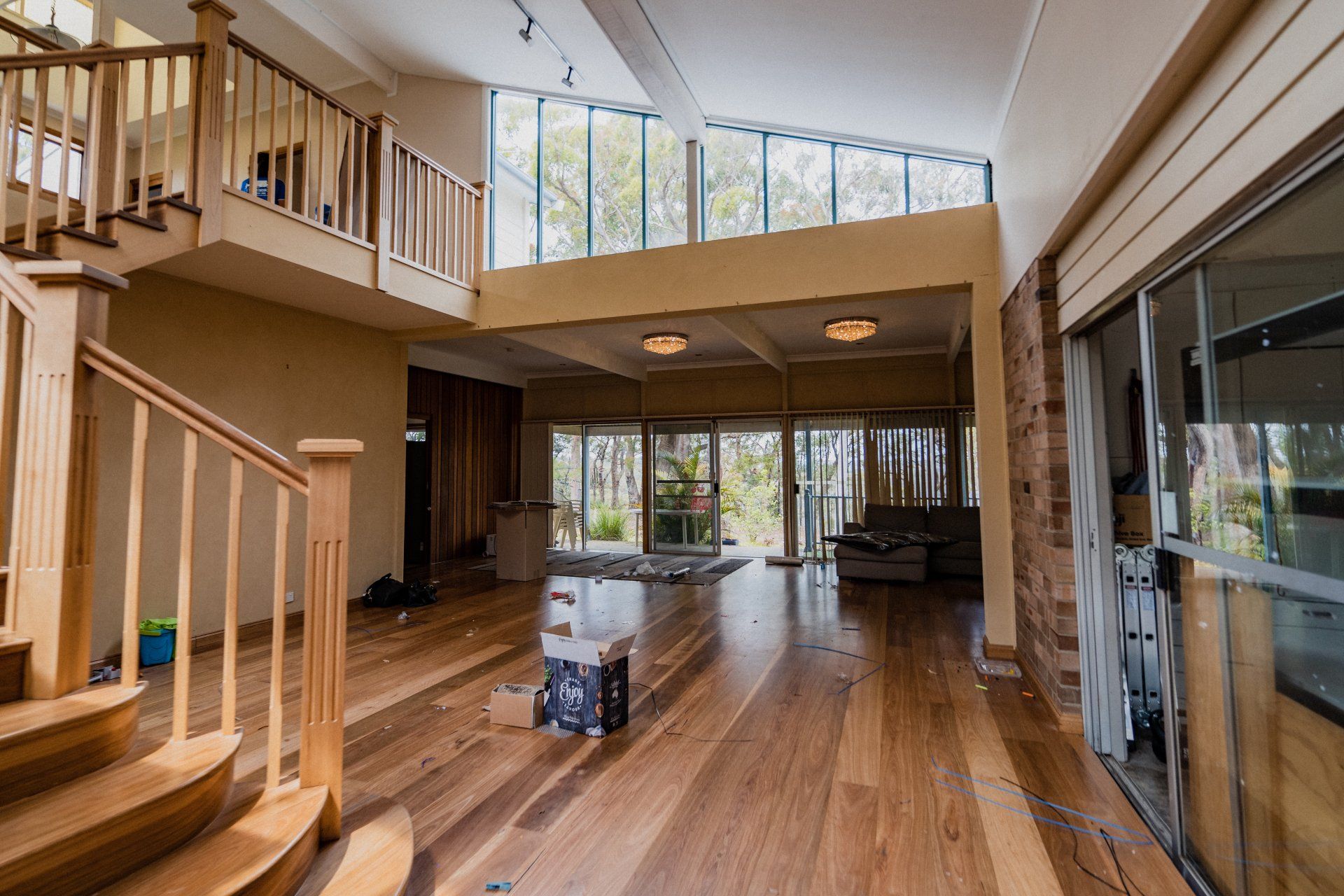 Spacious living room with hardwood floors, staircase, large windows, and sliding glass doors to the outdoors