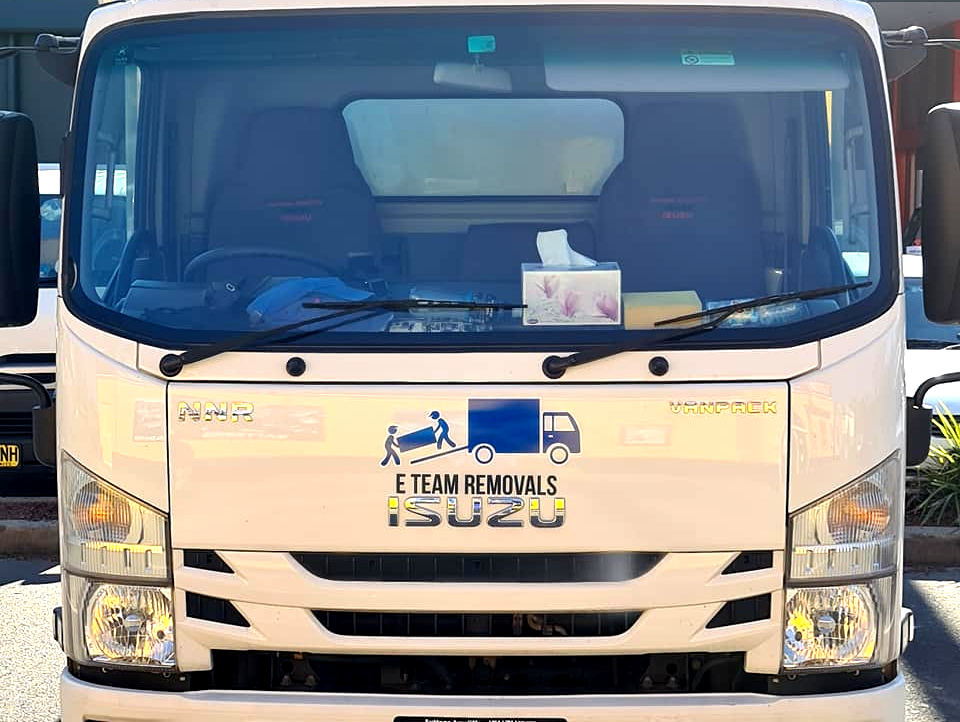 Front view of a white delivery truck with a logo on the grille, parked outdoors