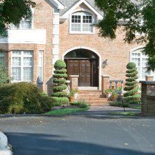 The front of a large brick house with trees in front of it.