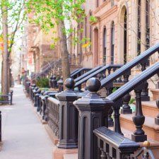 A row of houses with stairs leading up to them on a city street.