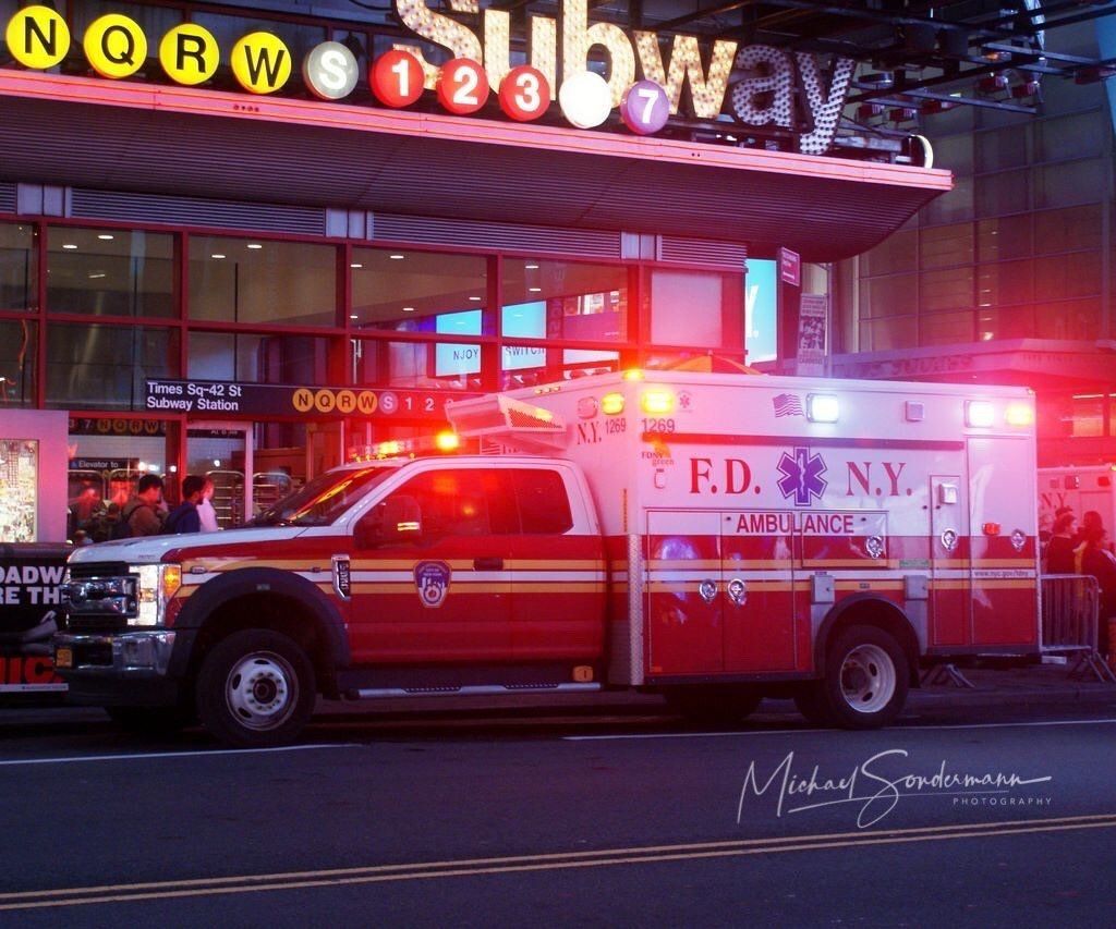 An ambulance is parked in front of a subway station