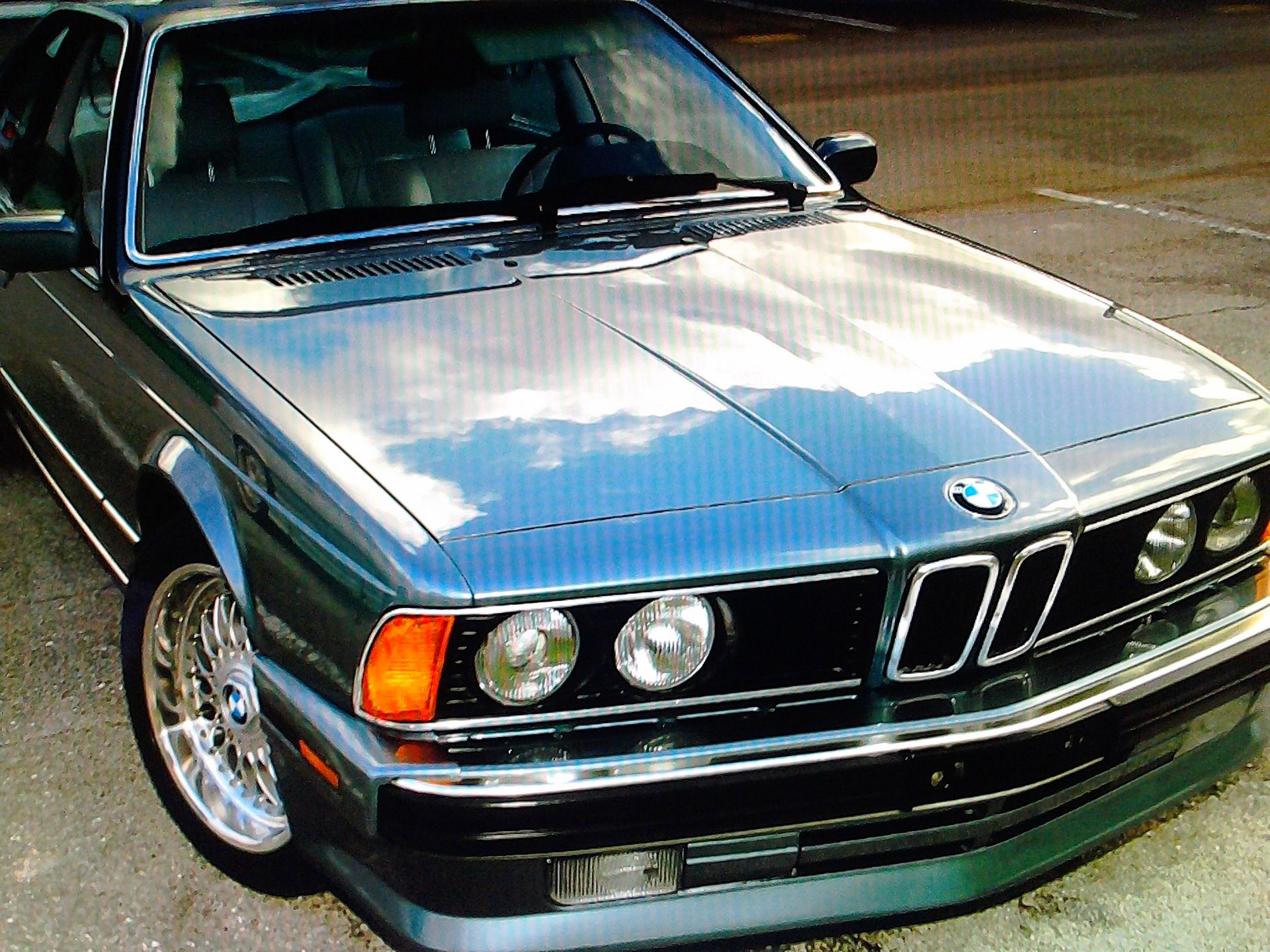 A blue bmw is parked on the side of the road