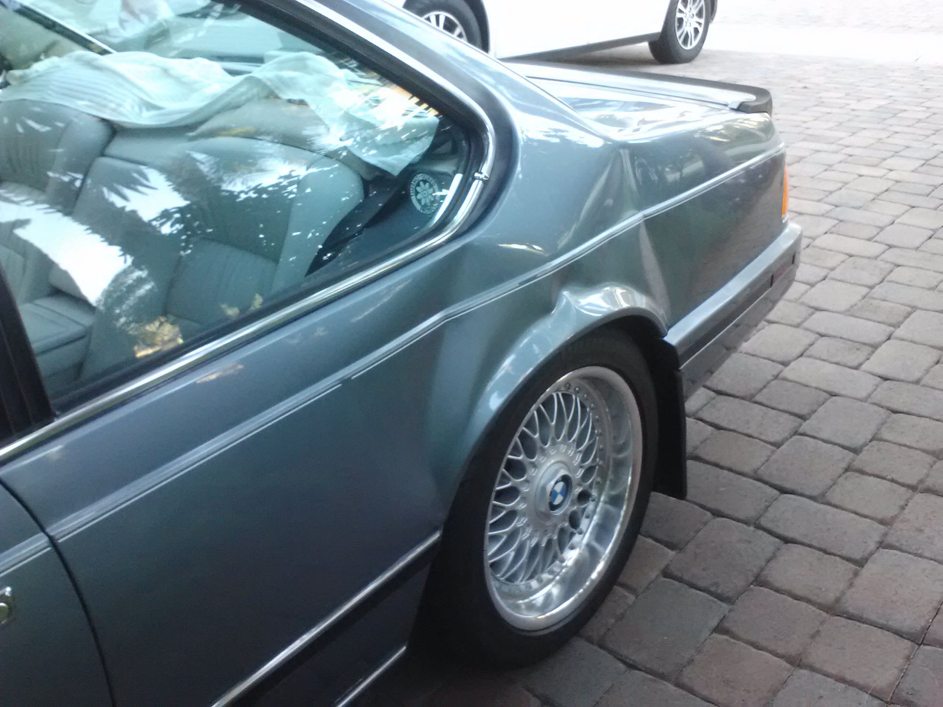 A bmw car is parked on a brick driveway