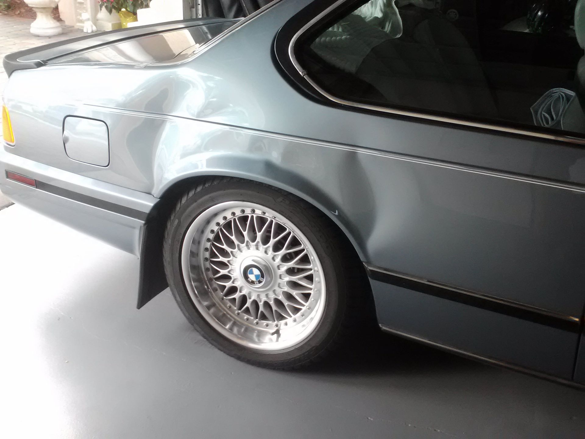 A car with a damaged side is parked in a garage