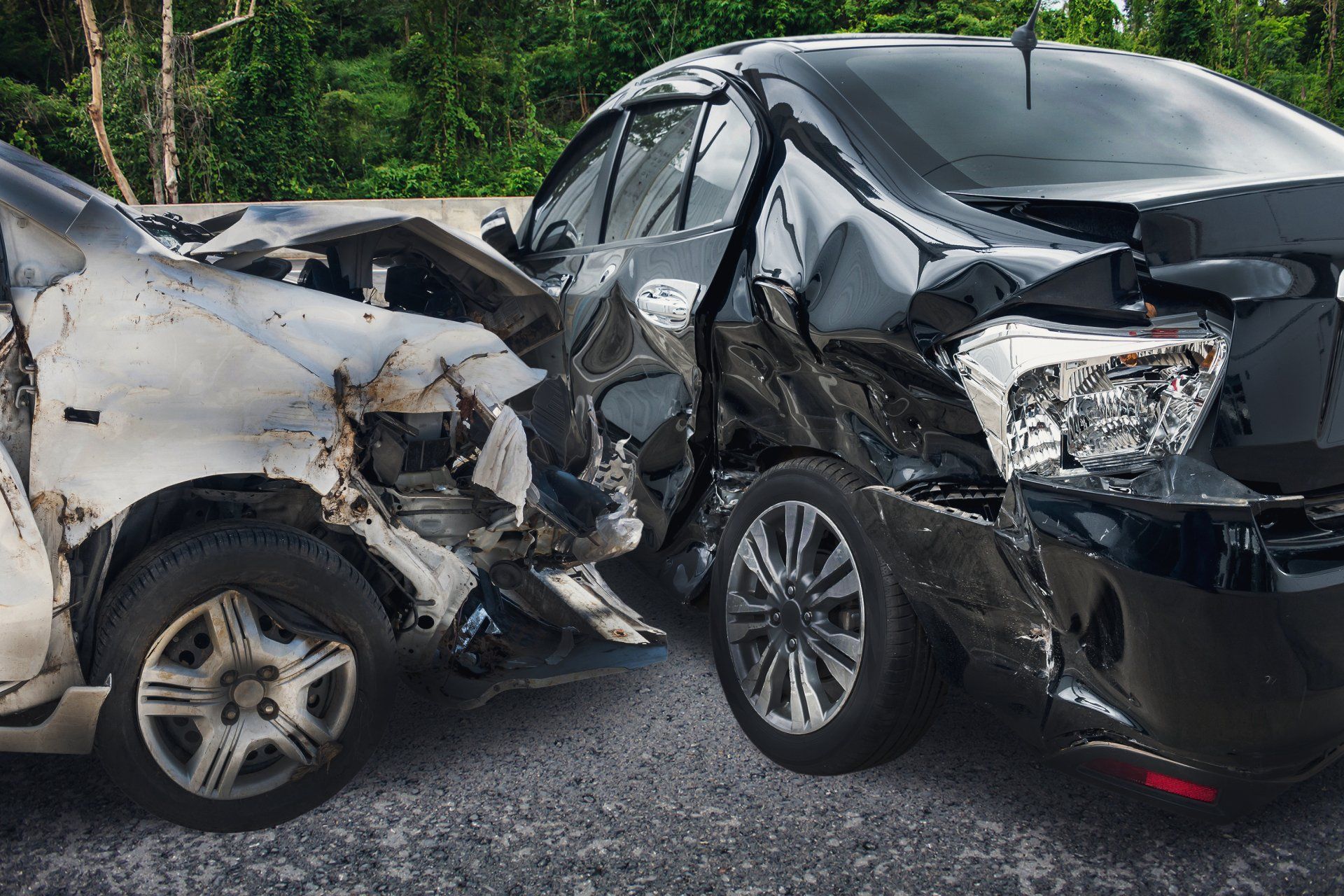 Two cars are damaged in a car accident on a road.