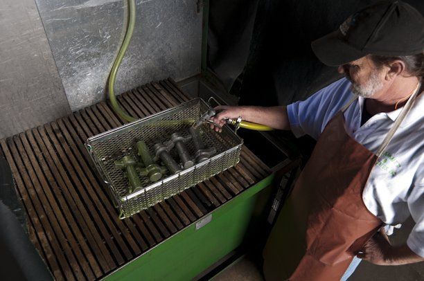 A man in an apron is cleaning a basket with a hose
