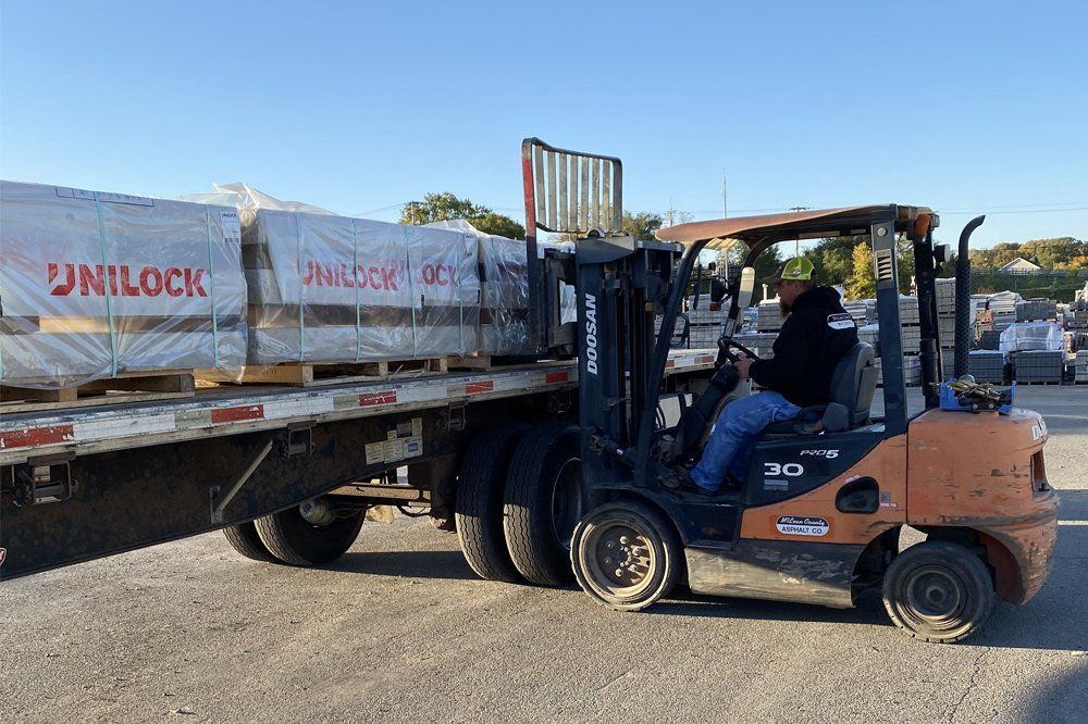 Worker Riding on a Vehicle Getting Materials — Bloomington, IL — McLean County Asphalt Co.