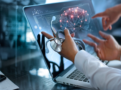 A doctor is holding a stethoscope in front of a laptop