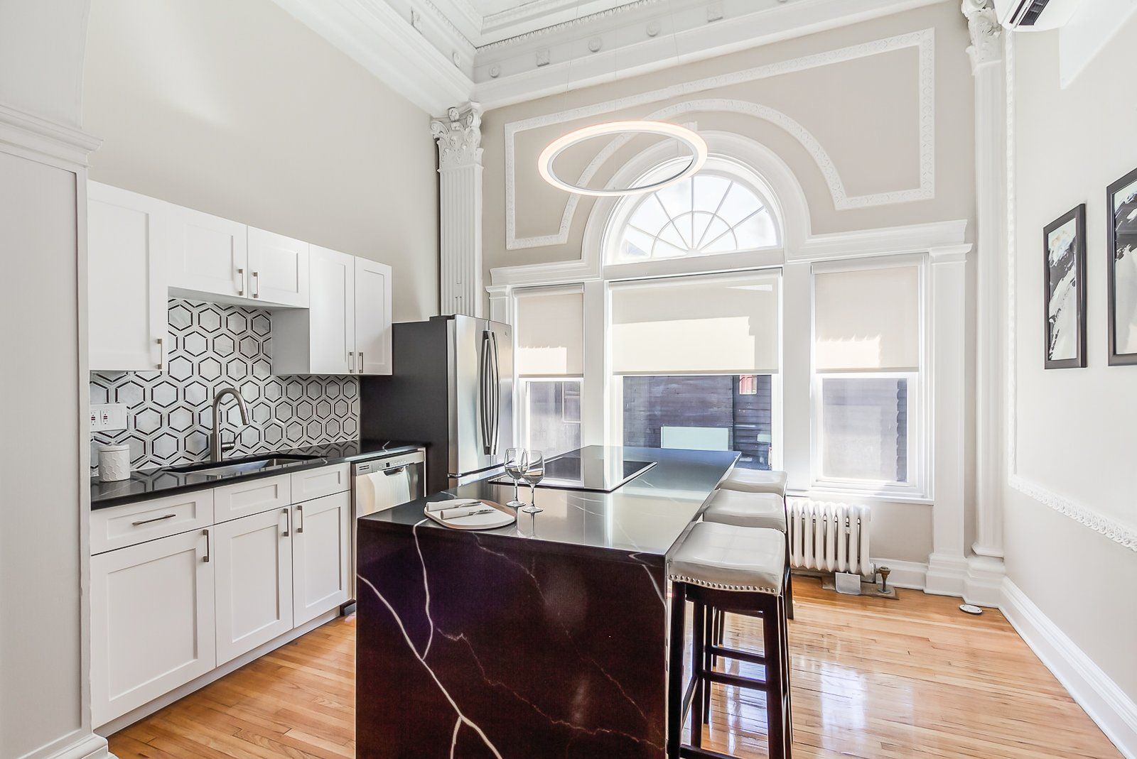 Renovated ballroom kitchen with modern backsplash, kitchen island, and stainless steel appliances