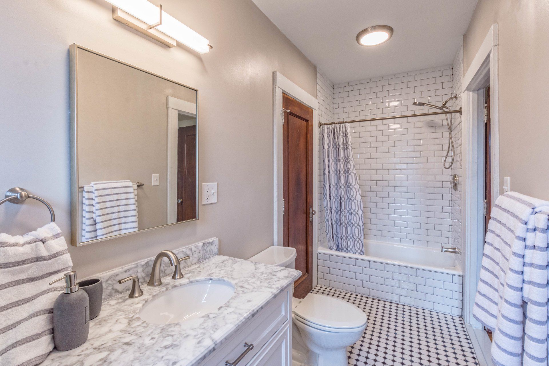 Renovated bathroom with charming black-and-white tiles and wooden doors