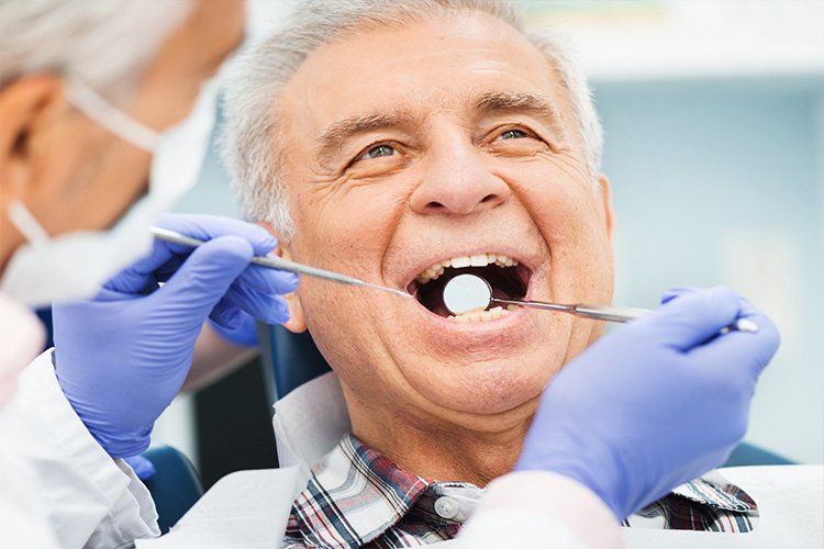 An elderly man is having his teeth examined by a dentist.