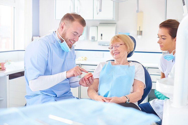 A woman is sitting in a dental chair talking to a dentist.