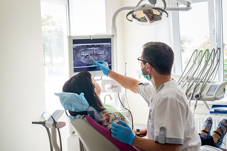 A dentist is looking at an x-ray of a patient 's teeth.
