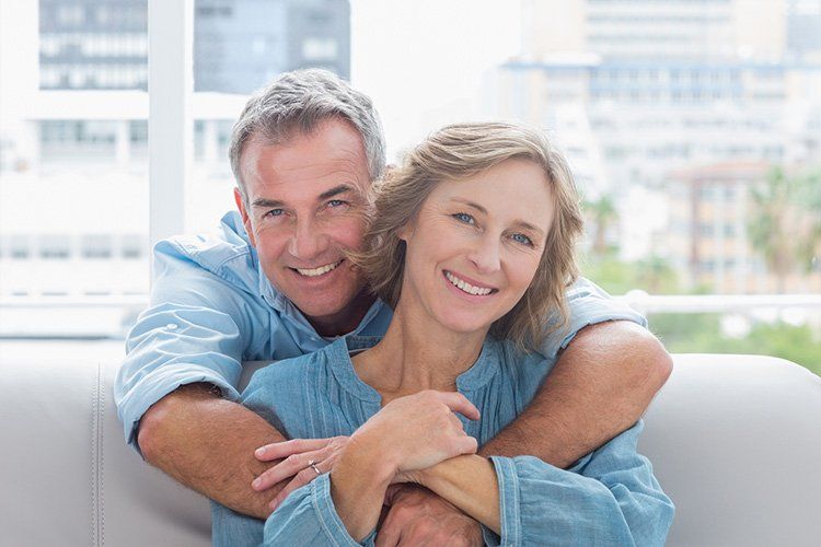 A man and a woman are sitting on a couch hugging each other.