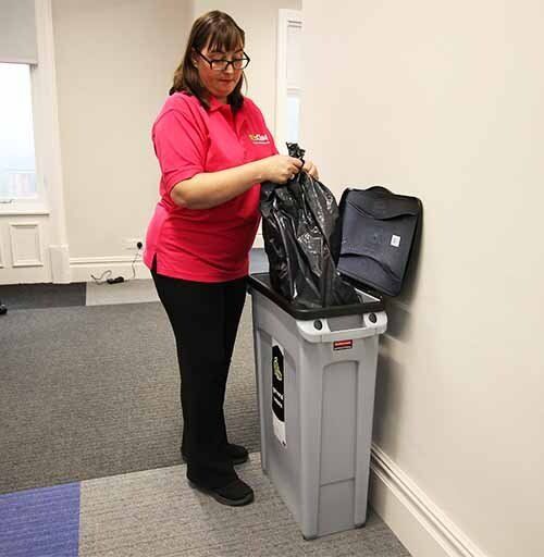 Office cleaner emptying waste bin