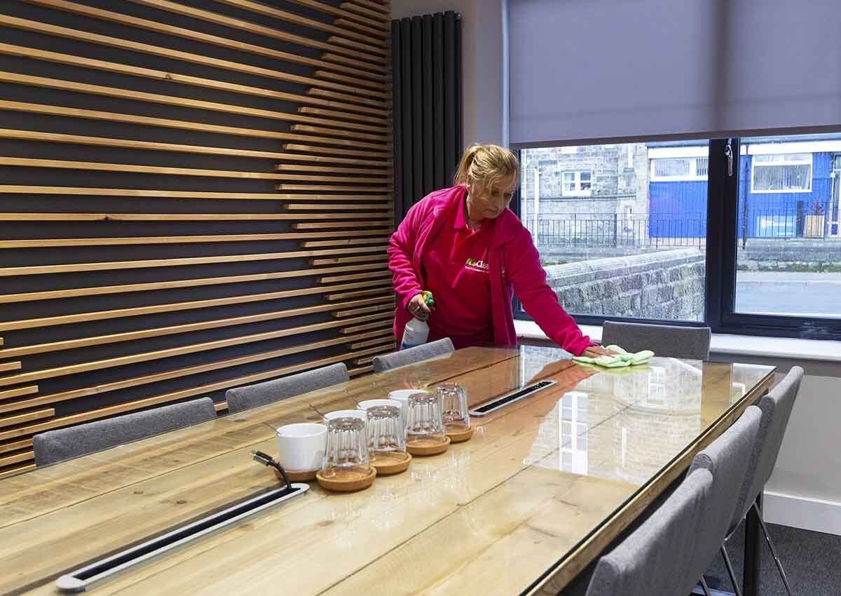 Cleaning Harrogate office meeting room table top with microfibre cloth
