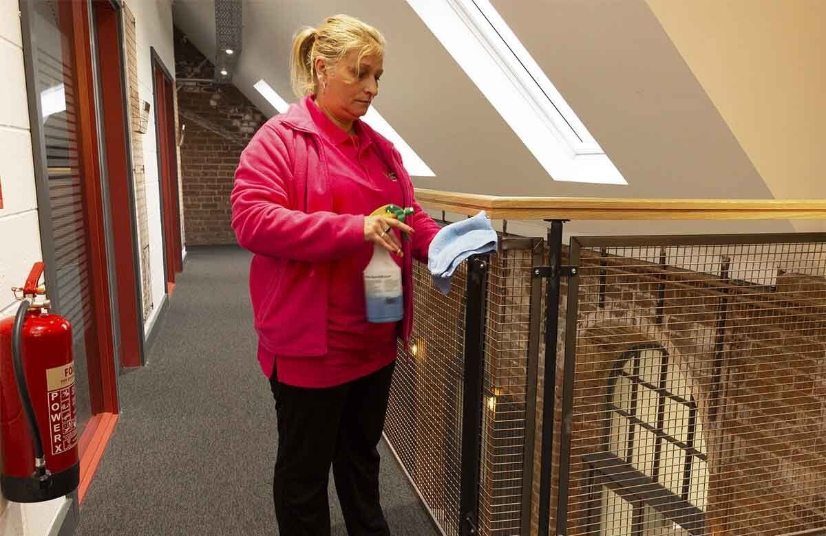 Cleaning banister of office walkway