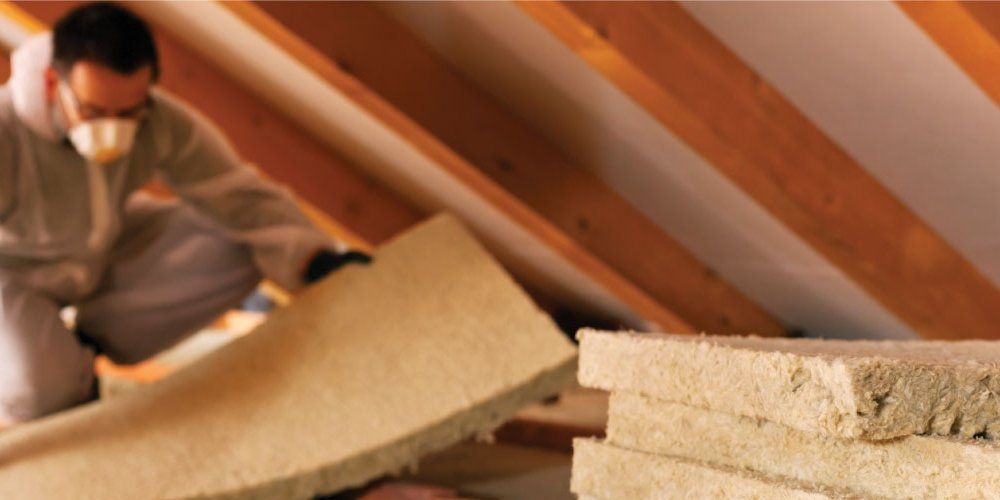 A man wearing a mask is working in an attic