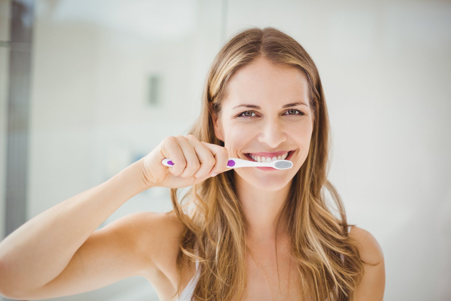 Woman Cleaning Teeth at Bathroom — Eastpointe, MI — Eastland & Professional Dental Center Woman Cleaning Teeth at Bathroom — Eastpointe, MI — Eastland & Professional Dental Center