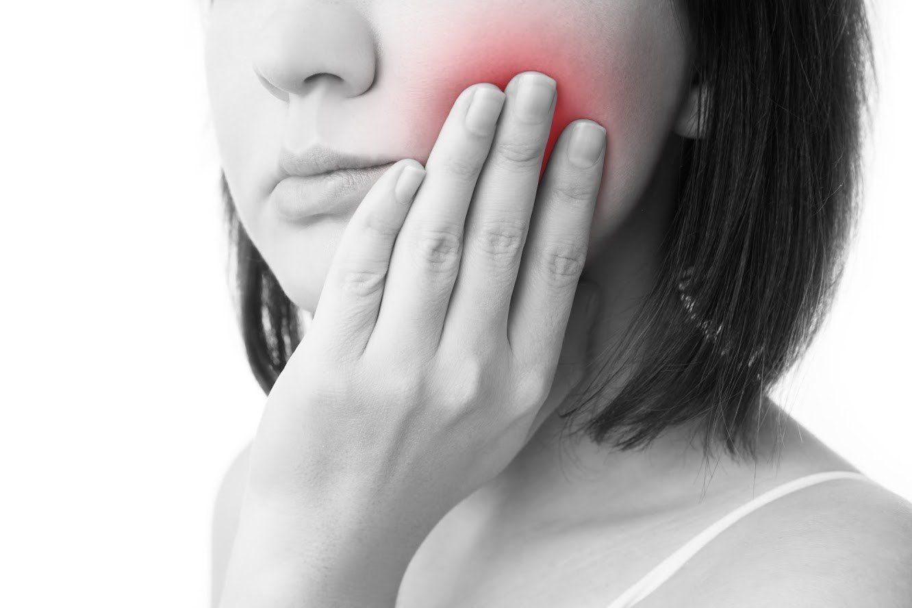 Woman Holding Cheeks — Eastpointe, MI — Universal Dental Center Woman Holding Cheeks — Eastpointe, MI — Universal Dental Center