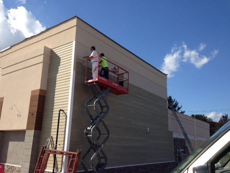 Worker painting high rise building with roller in East Haven
