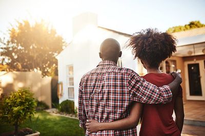 A hugging couple looks at their new home.