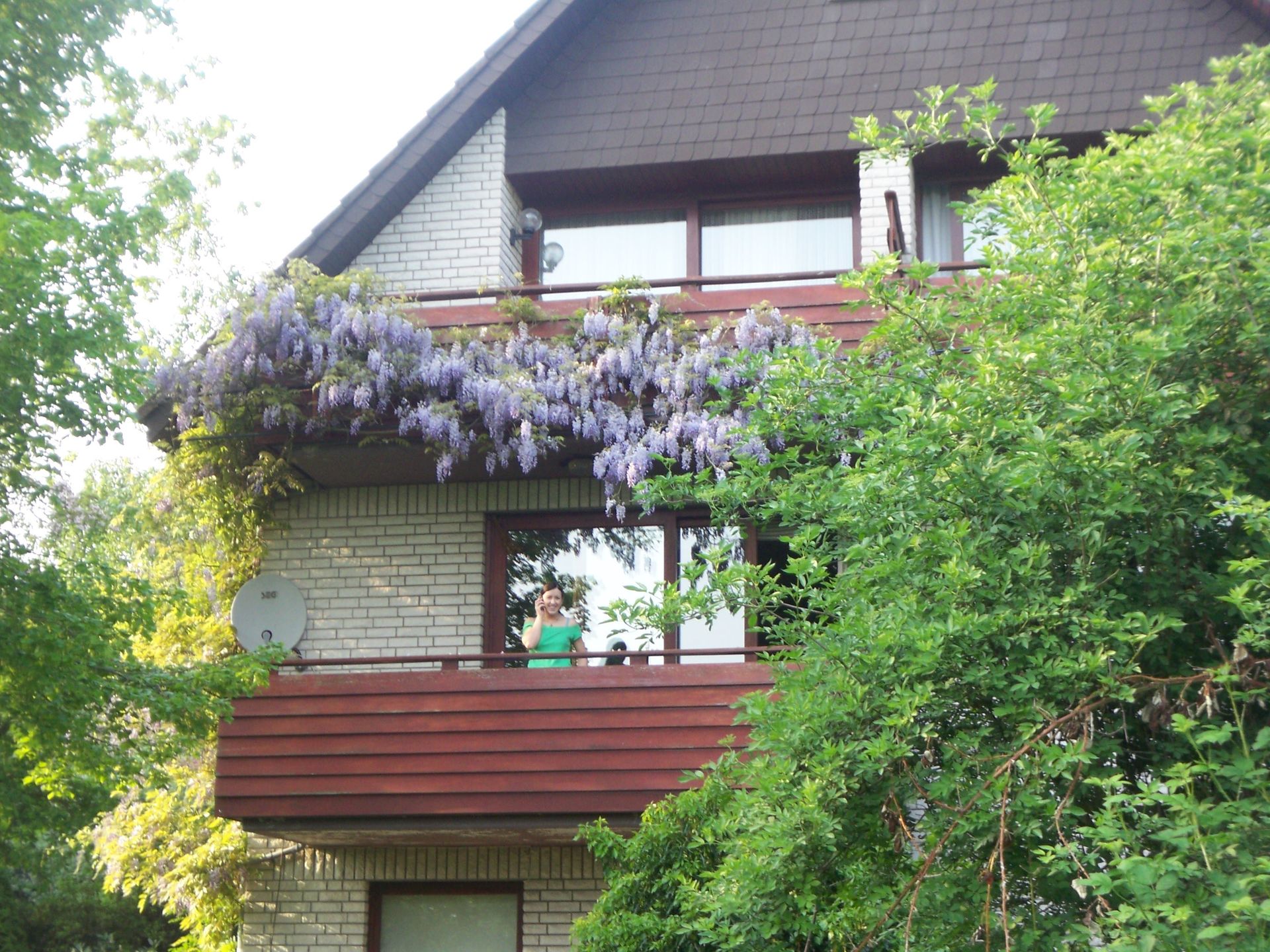 Ein Haus mit einem Balkon und lila Blumen darauf