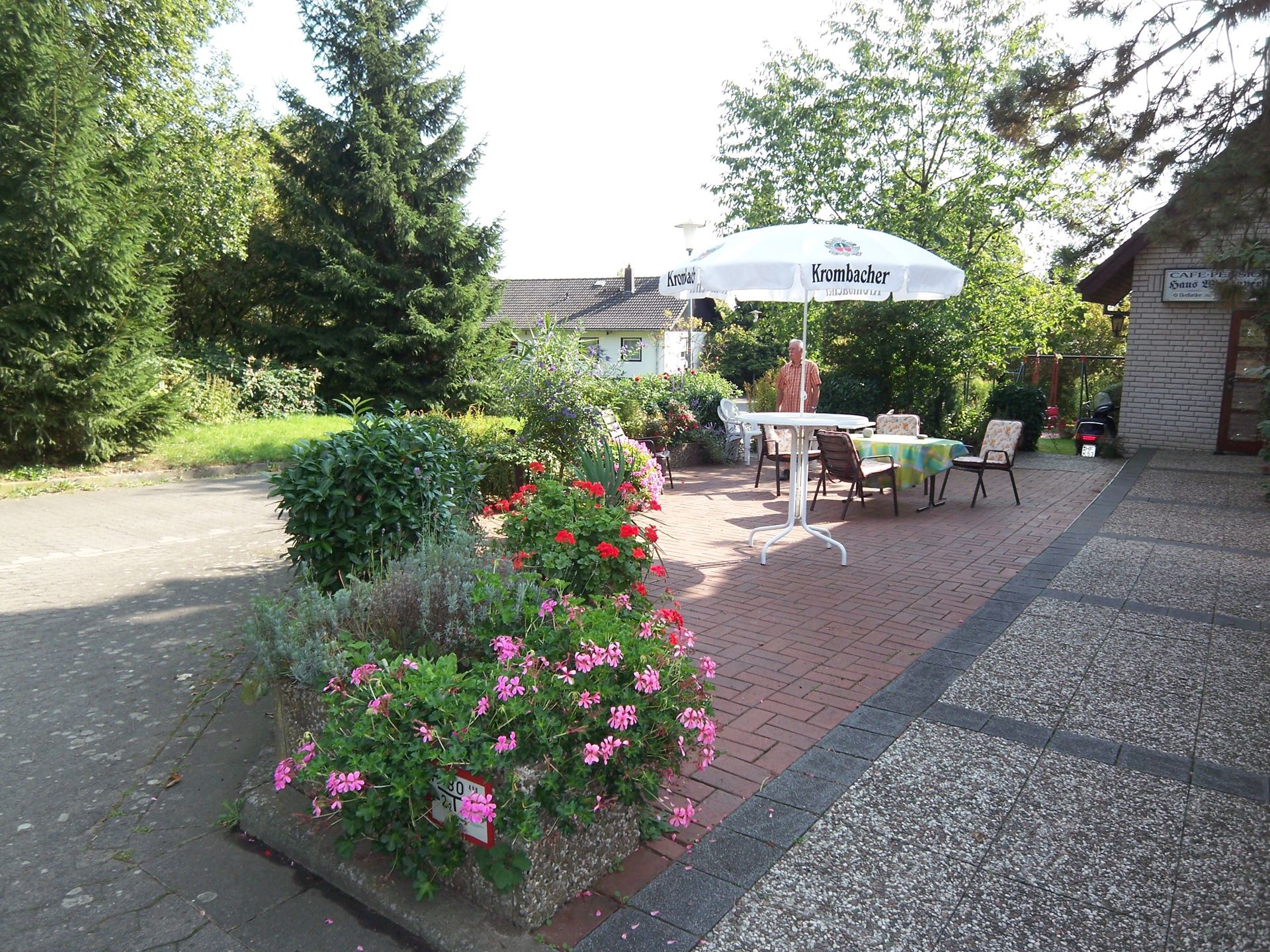 Eine Terrasse mit Tisch und Stühlen und einem weißen Sonnenschirm