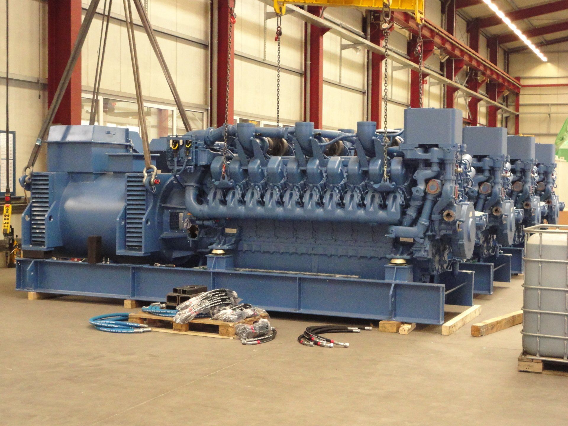 Un gros moteur bleu est posé sur une palette en bois dans un entrepôt