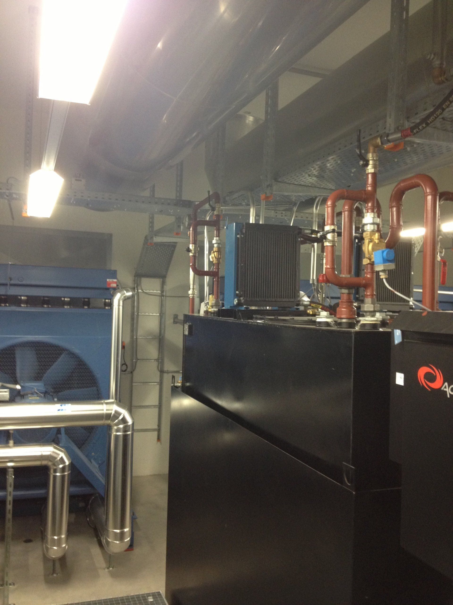 Une pièce avec beaucoup de tuyaux et une machine sur laquelle est écrit qp