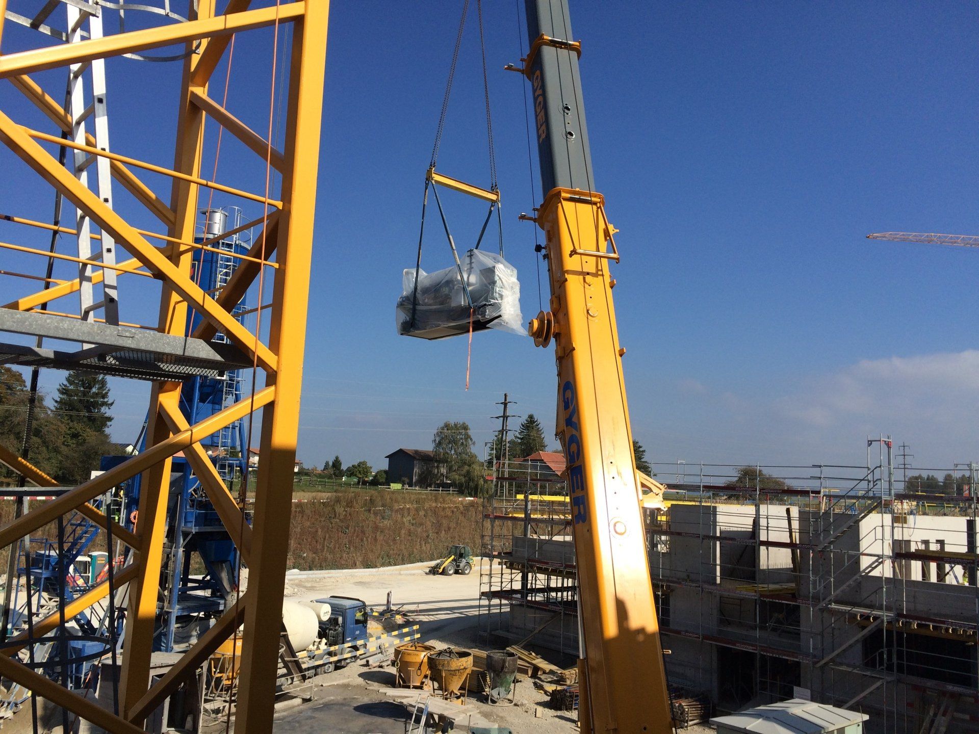 Une grande grue soulève un gros objet sur un chantier de construction