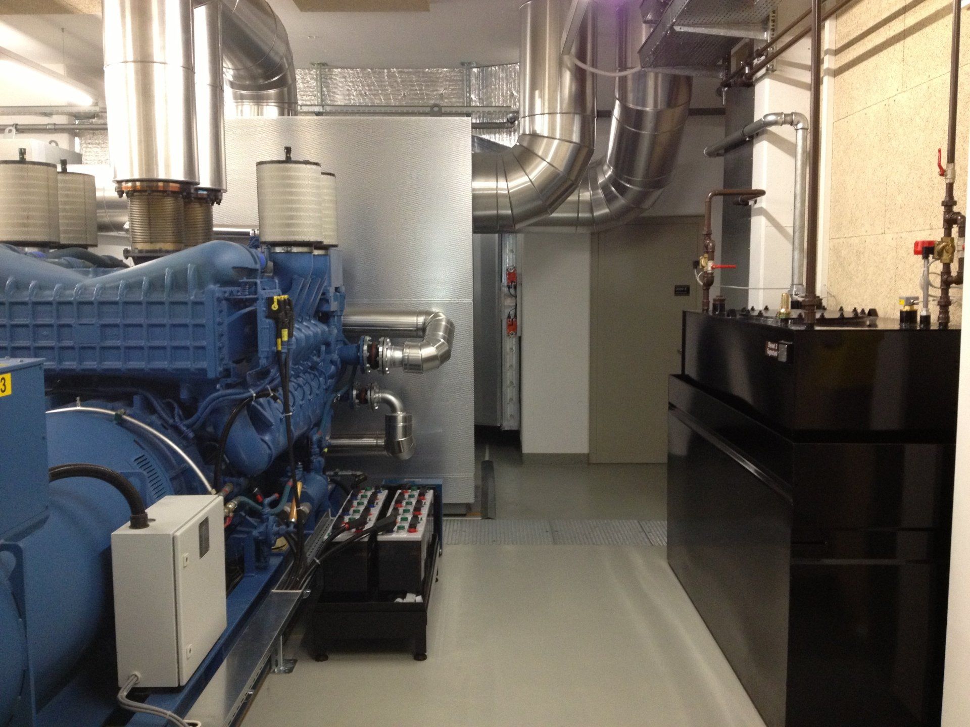 Un gros moteur bleu est assis dans une pièce à côté d'un réservoir noir.