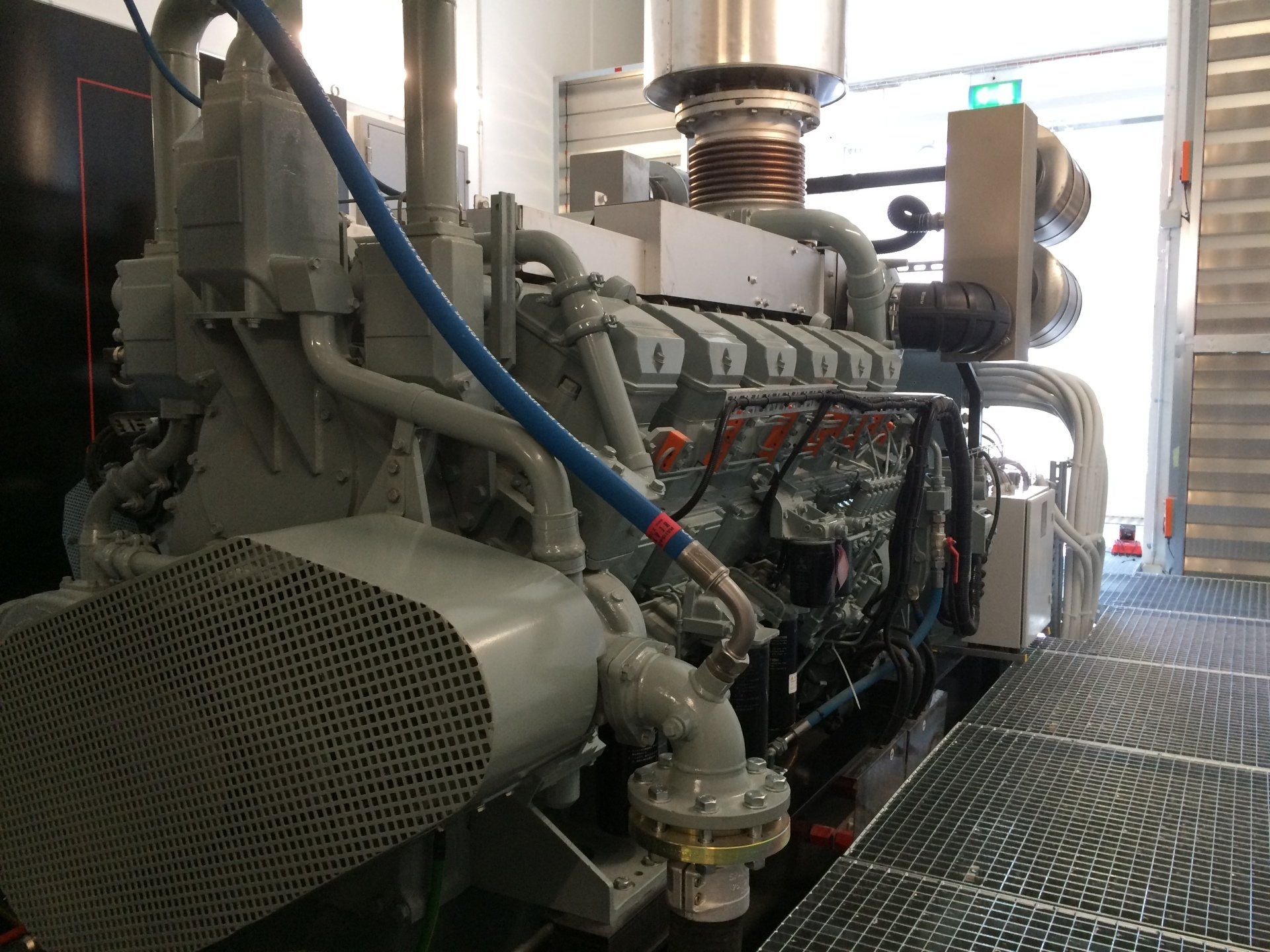 Un gros moteur est assis dans une pièce avec un tuyau bleu attaché à lui.