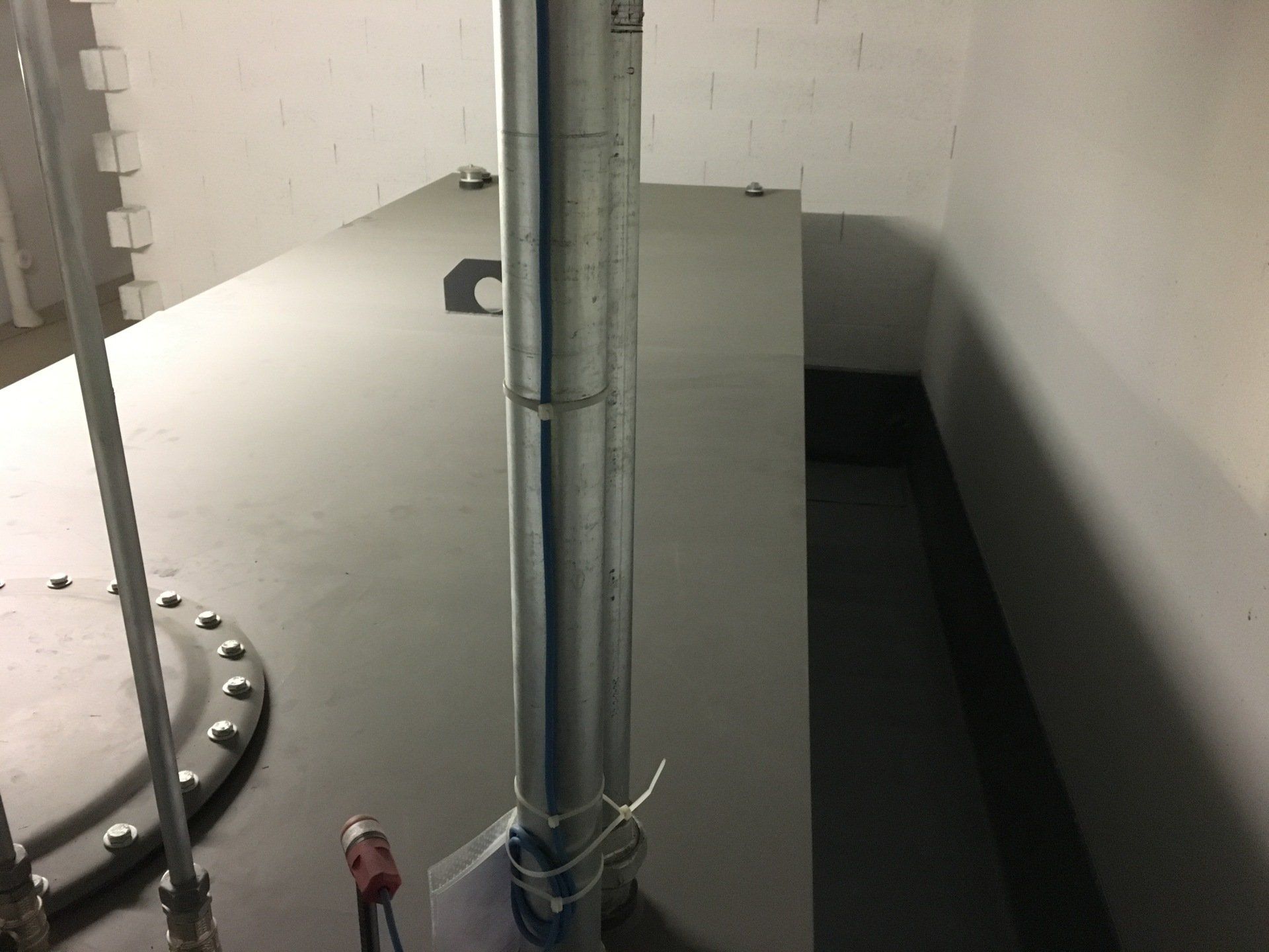 Un tuyau métallique est posé sur un sol en béton dans une pièce.