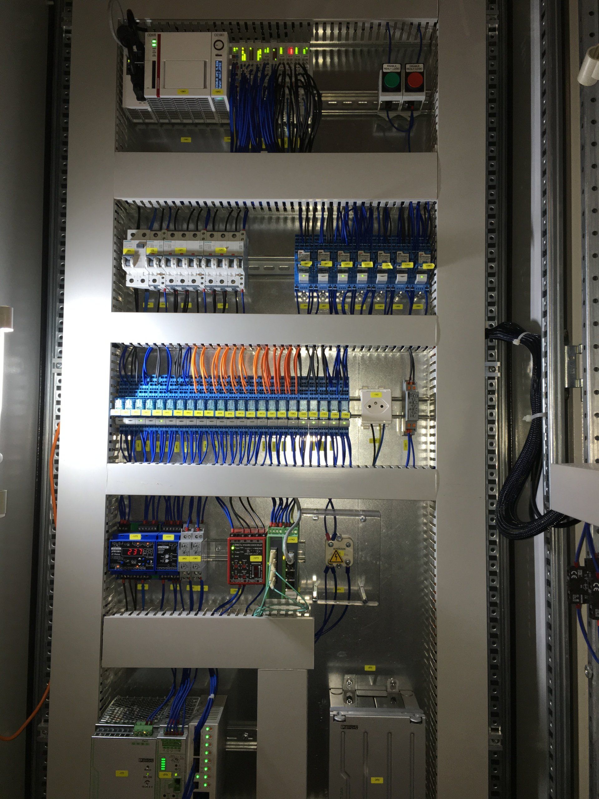 Un grand panneau de contrôle électrique avec beaucoup de fils qui en sortent.