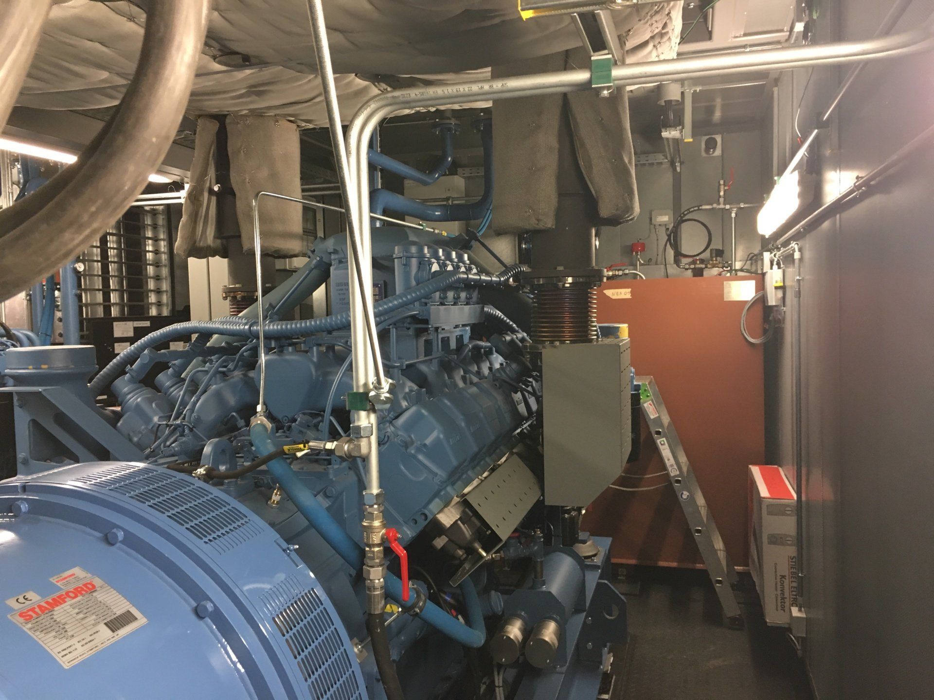 Un gros moteur bleu est assis dans une pièce à côté d'une échelle.