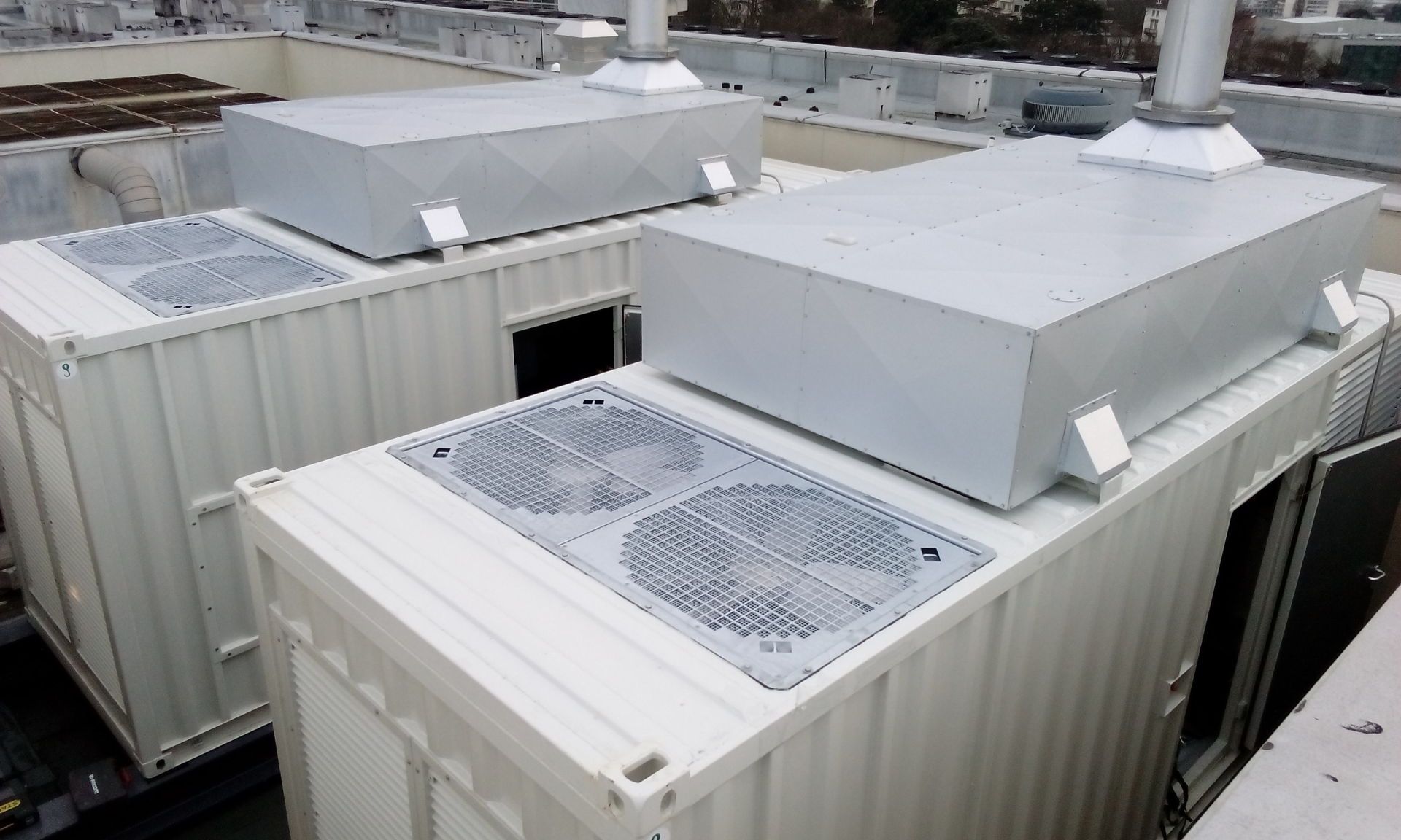Une rangée de conteneurs d'expédition blancs avec des ventilateurs au-dessus.