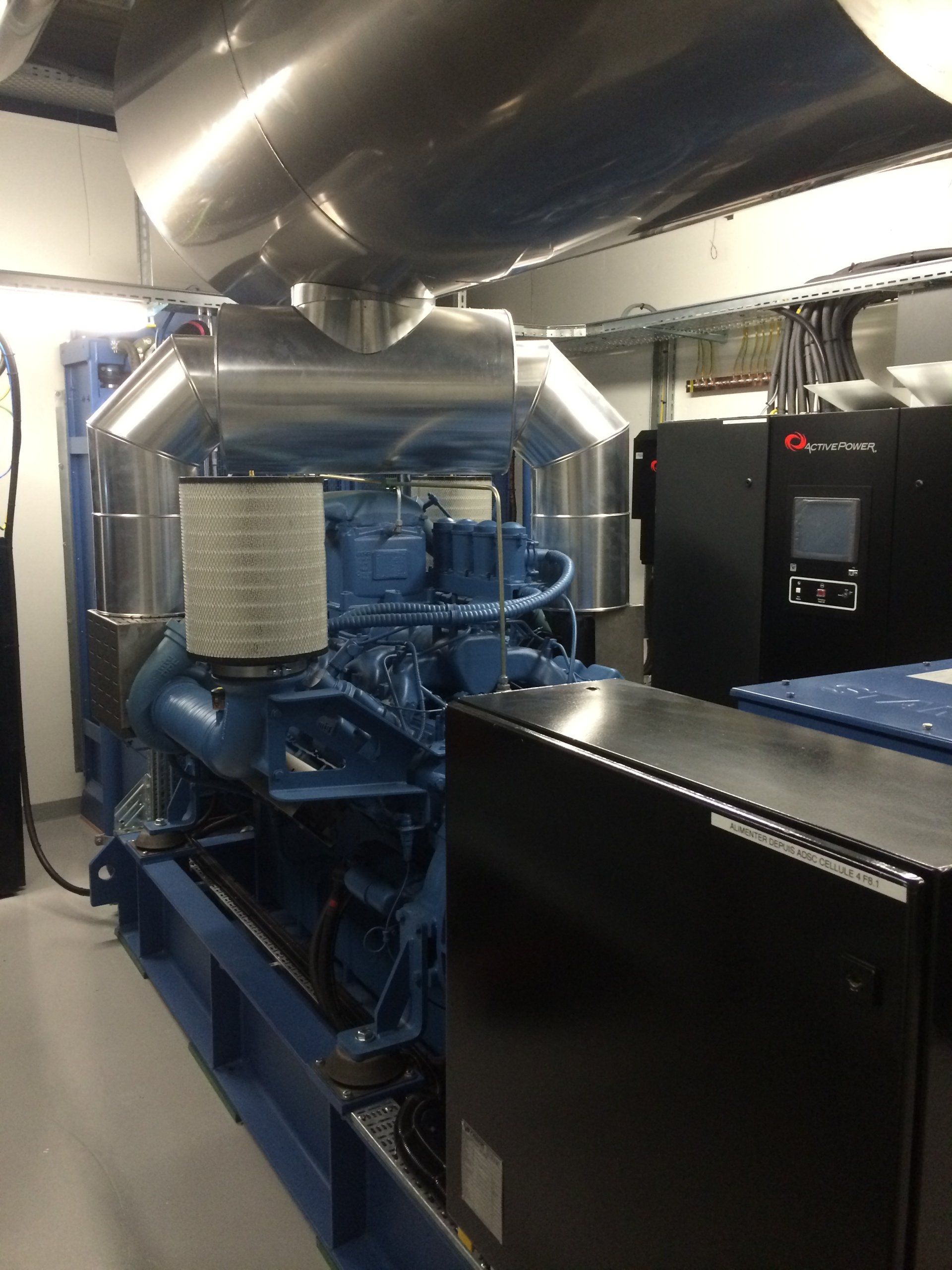 A large blue engine is sitting in a room next to a black box.